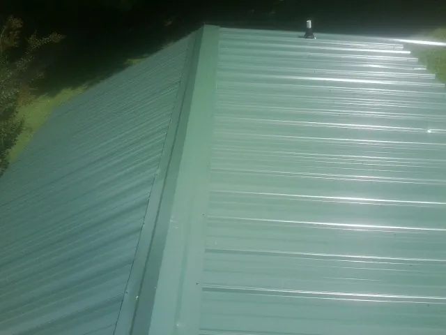 New green metal panels meeting at the ridge of a roof — Flat Roof Repair work by our crew in Truxton