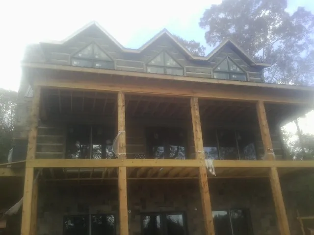 Dormers and porch framing on a large log home under construction — Roof Coating work by our crew in Truxton