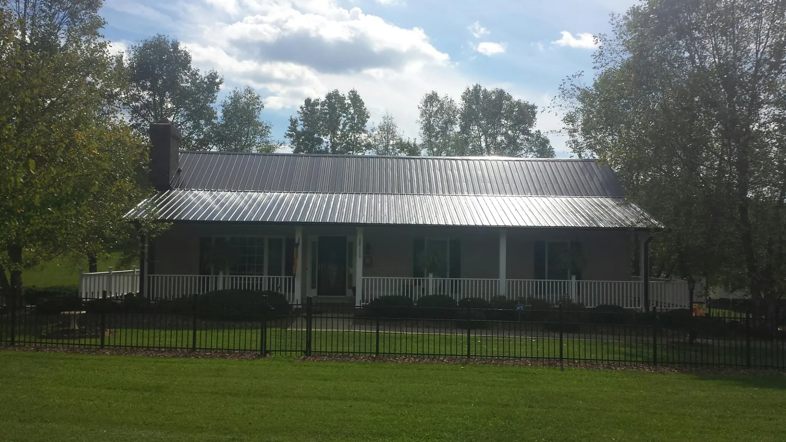 Gray metal roof on a brick ranch with a full width front porch — Gutter Guard Installation work by our crew in Truxton